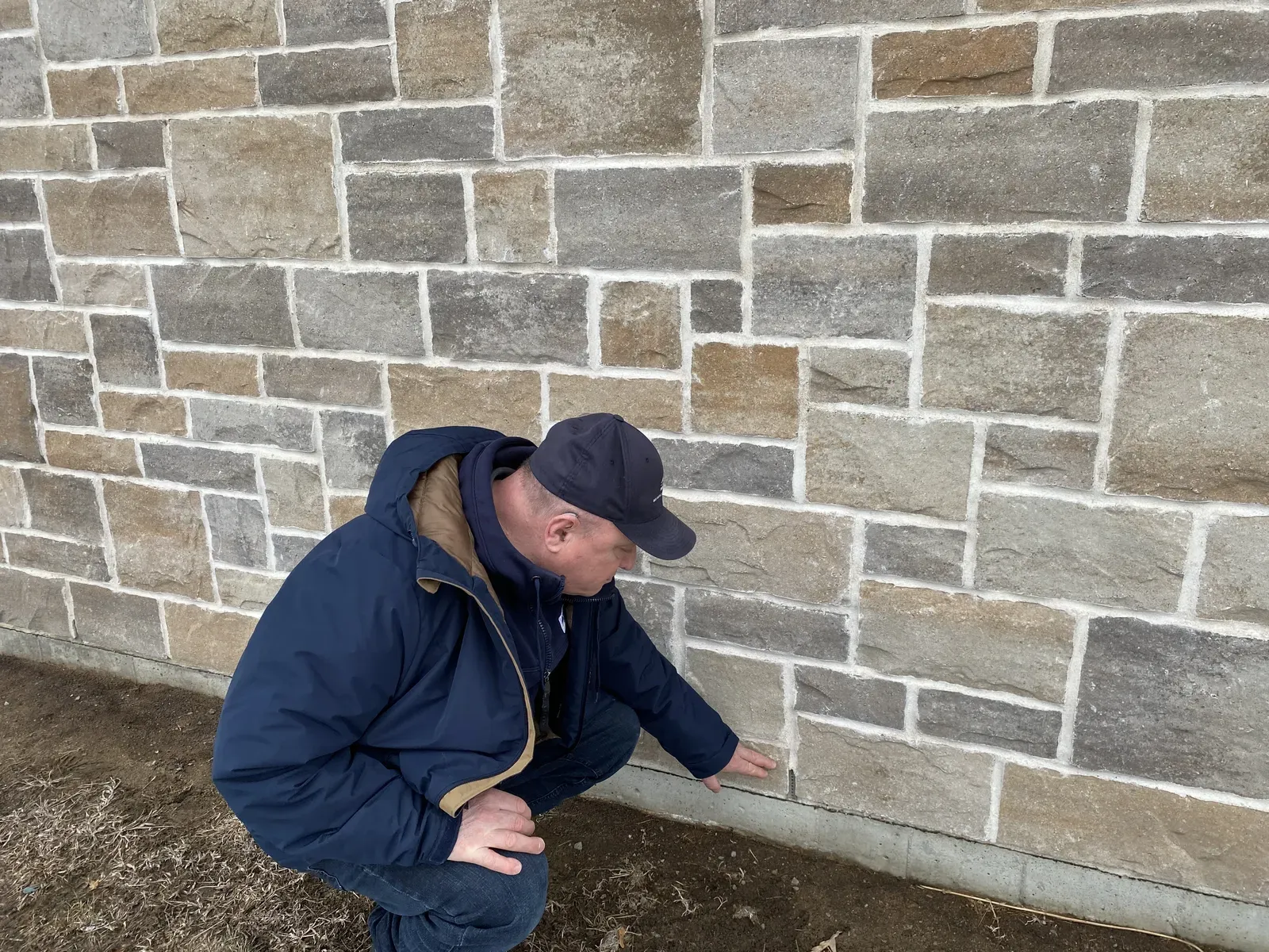 Inspecteur vérifiant les chantepleures de brique lors d'une inspection prévente à L'Assomption