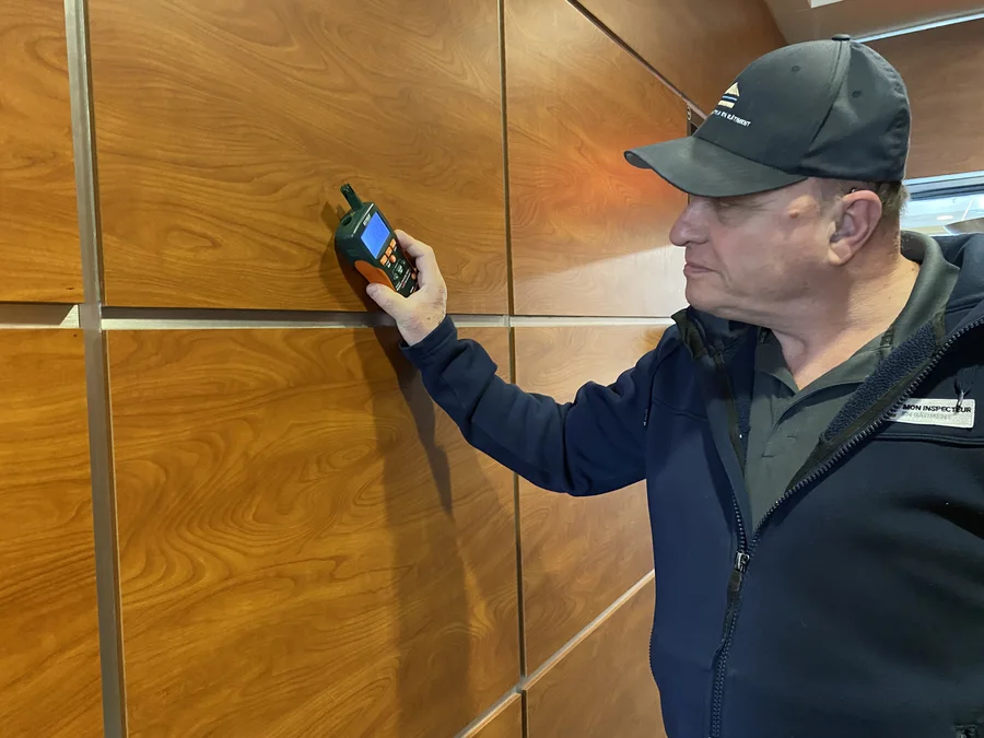 Un inspecteur en bâtiment utilise un détecteur d'humidité sur un panneau de bois mural à Sainte-Thérèse.