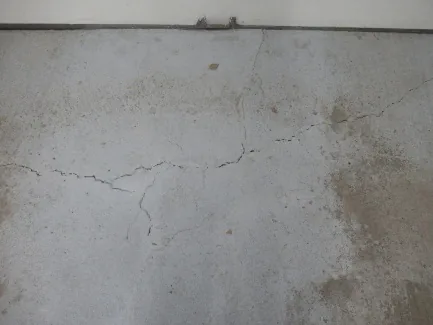 Fissures et gonflement sur une dalle de béton au sol causés par la pyrite dans le secteur Monteuil.