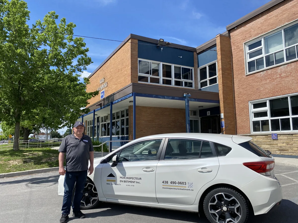 Inspecteur en bâtiment certifié selon la norme BNQ 3009-500 devant l'école primaire Sainte-Béatrice à Auteuil, Laval avec son unité mobile.