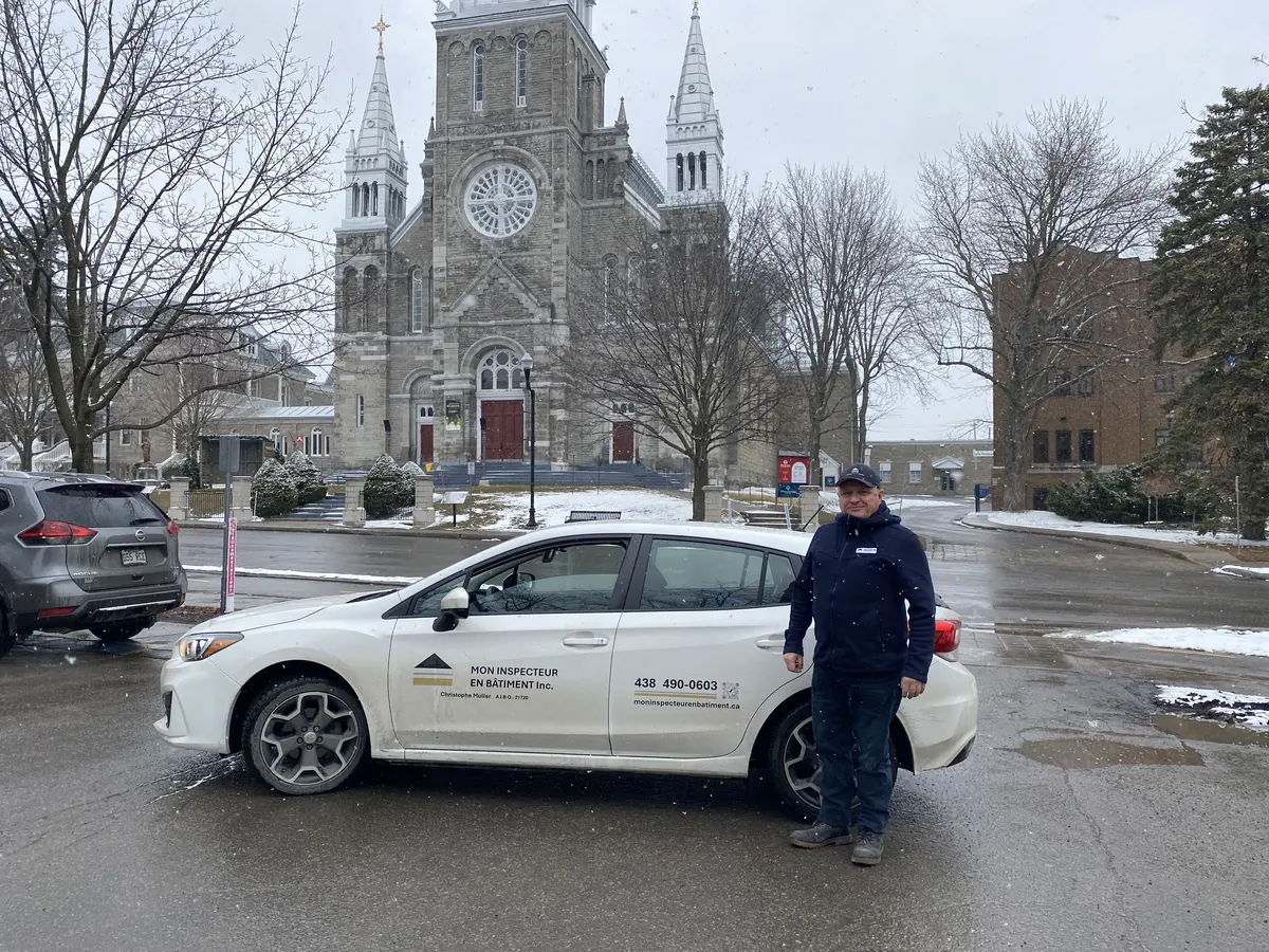 Inspecteur en bâtiment devant l'église Sainte-Thérèse-d'Avila avec le véhicule de service de Mon inspecteur en bâtiment Inc.